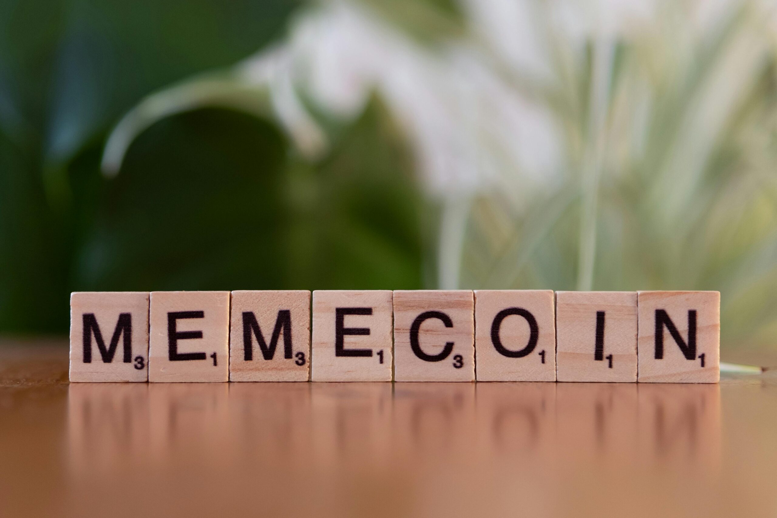 10 Ideen für nebenberufliches Geldverdienen online 1 Holzfliesen mit der Aufschrift „Memecoin“ auf unscharfem Hintergrund.